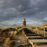 Stufen führen zu einem Leuchtturm auf Sylt mit grauen Wolken.