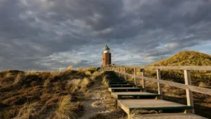 Stufen führen zu einem Leuchtturm auf Sylt mit grauen Wolken.